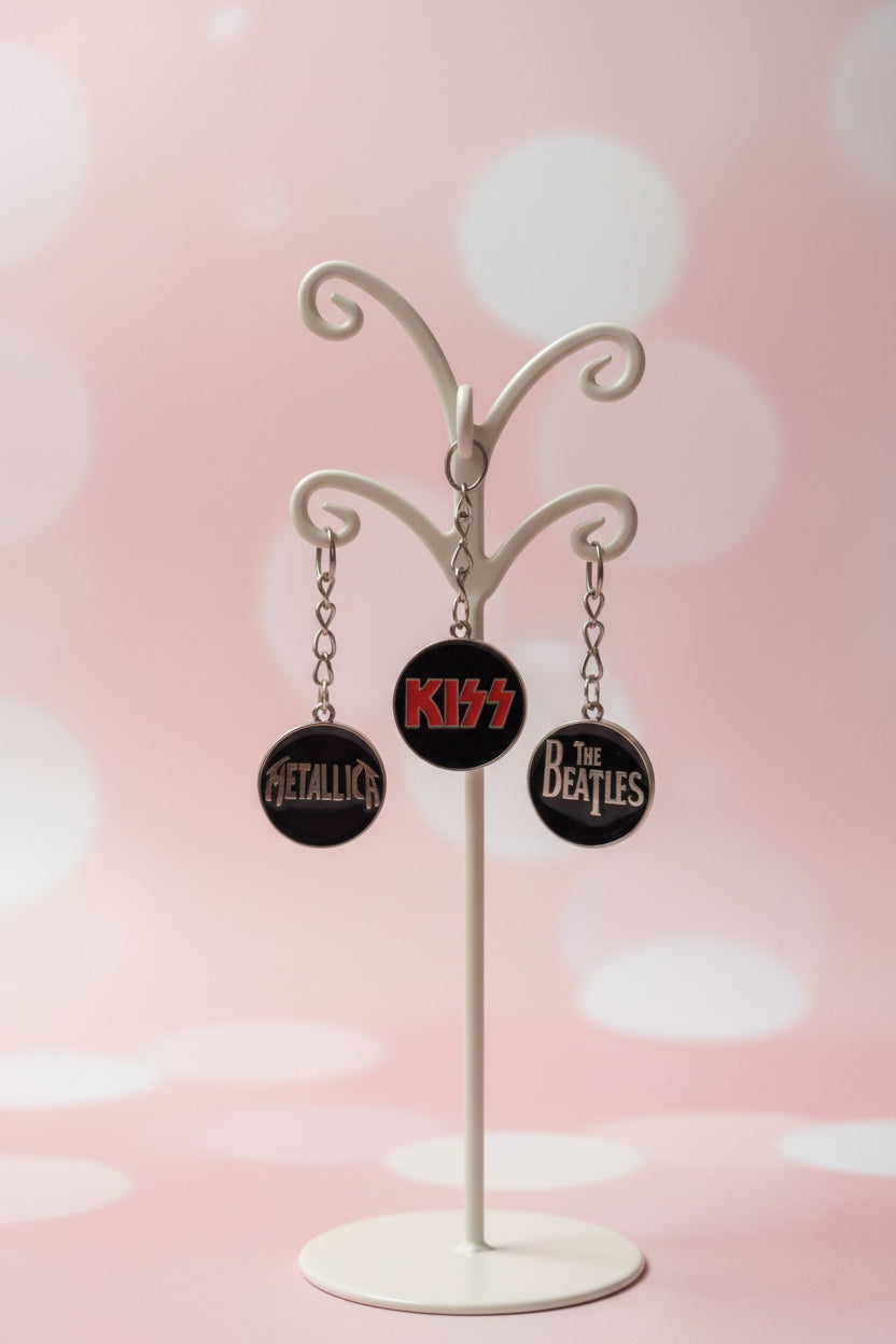 Carolinas Beautiful Jewerly set med tre runda nyckelringar i metall och emalj med logotyper för Metallica, Kiss och The Beatles.